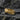 Side profile view of gold vermeil wolf ring with flowing fur texture displayed on textured dark rock background