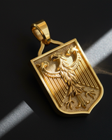 Gold vermeil German Eagle pendant on black background showing detailed shield texture and raised relief