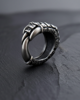 Angled view of silver bird talon ring wrapping around finger form