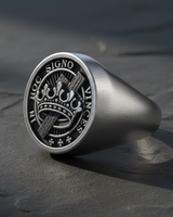 Angled view of handcrafted silver masonic ring showing thick band and detailed oxidized signet face on stone background