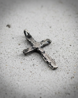 Close-up of hammered texture on silver cross pendant showing rugged edges and vintage style
