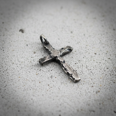 Close-up of hammered texture on silver cross pendant showing rugged edges and vintage style