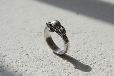 Side profile of silver gothic ring showing skeletal arm band details and oxidized finish for depth