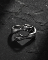 Front view of adjustable sterling silver embrace ring with hands overlapping in a hug gesture