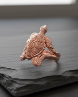 Detailed rose gold plated turtle ring showing intricate shell pattern on dark slate background