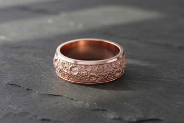 Rose gold plated 925 sterling silver lunar crater ring with textured moon surface design on dark stone background