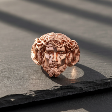 Rose gold plated silver Jesus ring with a detailed crown of thorns, shown from the front on a dark slate surface.