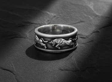 Side view of charging bull relief carved into a 925 sterling silver ring band on dark texture