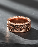 Rose gold vermeil Silver Fleur-de-lis Ring with milgrain edges, casting a shadow on a textured black surface.
