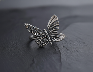 Front view of handcrafted silver butterfly ring with one floral wing and one smooth wing on dark stone
