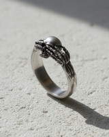 925 sterling silver death claddagh ring featuring skeletal hands holding a skull on textured stone background