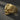 A 3/4 view of the skull cross ring design in a polished gold finish, highlighting the menacing expression and winged band.
