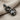 Bow Tie Cat Pendant, black rhodium, angled view on linen