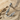 Close-up of handcrafted Bird Letter U Pendant in 925 sterling silver resting on natural sand and driftwood.