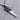 Close-up of artisan hand saw pendant showcasing the dark oxidized silver finish resting on a textured wood log