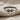 Close-up of oxidized silver petite bow ring resting on textured linen cloth showcasing intricate center knot details