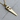 Close-up macro shot of the hand saw pendant resting on a wooden surface, highlighting the detailed craftsmanship