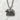 Front view of handcrafted sterling silver Hokkaido bear pendant resting flat on a textured white stone background.