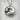 Handcrafted Great Wave medallion pendant resting on textured concrete, highlighting the dimensional silver waves.