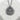 Handcrafted silver Japanese onsen pendant resting on a textured white stone surface showing matte finish details
