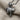 Close-up of handcrafted thumbs down pendant resting on textured linen fabric highlighting the oxidized silver finish