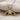 Close-up view of polished gold whale tail pendant with oxidized silver backing resting on beige linen fabric