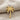 Detailed close-up of gold vermeil palm tree pendant lying on textured beige linen background detail view