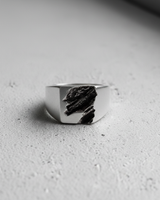 Black and white close-up of handcrafted silver ring highlighting the brutalist rift texture detail