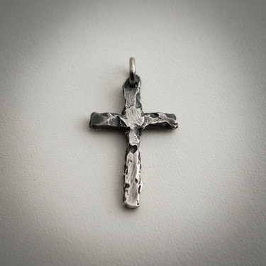 Angled view of textured silver cross necklace pendant highlighting heavy oxidation and artisan craftsmanship