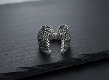 Handcrafted 925 sterling silver angel wings ring with detailed feather texture on black slate background