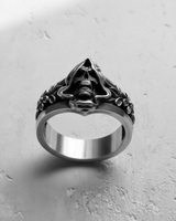 Detailed close-up of hooded skull ring for men displaying intricate floral carvings on the shank and polished silver texture