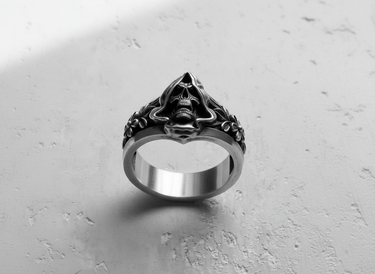 Detailed close-up of hooded skull ring for men displaying intricate floral carvings on the shank and polished silver texture