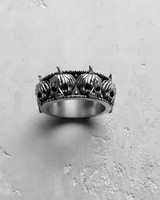 Close-up detail of grinning pumpkin skulls with beaded borders on handcrafted silver ring