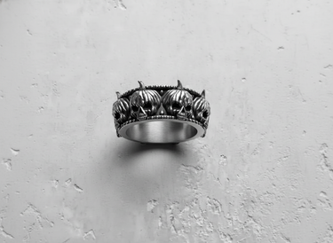 Close-up detail of grinning pumpkin skulls with beaded borders on handcrafted silver ring