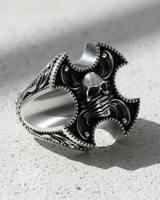 Angled side view of silver skull ring showing thick band, intricate baroque details, and silenced skull design
