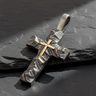 Angled view of handcrafted silver rustic cross pendant with gold vermeil center on dark slate background