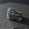 Front view of handcrafted 925 sterling silver cross shield ring on textured dark stone background
