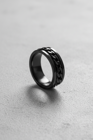 Black rhodium plated 925 sterling silver chain spinner ring standing upright on textured grey background