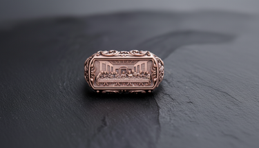Rose gold tone religious ring with ornate scrollwork on the sides and The Last Supper scene engraved on the bezel