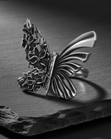 Side angle of 925 sterling silver butterfly ring showing intricate botanical carvings and oxidized finish