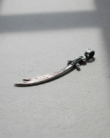 Close-up of handcrafted Islamic sword pendant with oxidized finish and polished silver chain loop