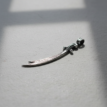 Close-up of handcrafted Islamic sword pendant with oxidized finish and polished silver chain loop