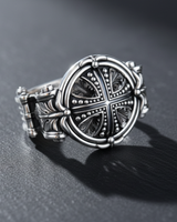 Oxidized sterling silver cross ring showing the detailed medieval-style carvings and intricate band on a slate background.