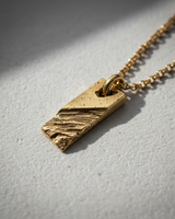 Side perspective of textured bar pendant highlighting handcrafted metalwork and sturdy bail loop design