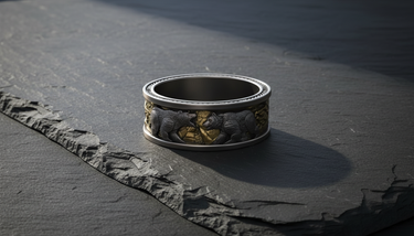 Angled view of wide band sterling silver bear ring with nordic design displayed on dark slate stone surface