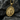 Close-up of gold Saint Martin of Tours medal showing halo and sword details resting on dark textured stone