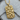 Detailed view of the gold vermeil skull dog tag pendant resting on a textured wooden log highlighting artisan craft