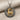 Close-up of Hittite deer pendant showing the hammered oxidized silver frame and detailed gold stag on fabric