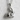 Sitting Rabbit Pendant in polished silver, product photo against textured wall