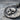 Close-up of hand-finished oxidized silver skull coin pendant showing detailed Latin inscription on rough stone